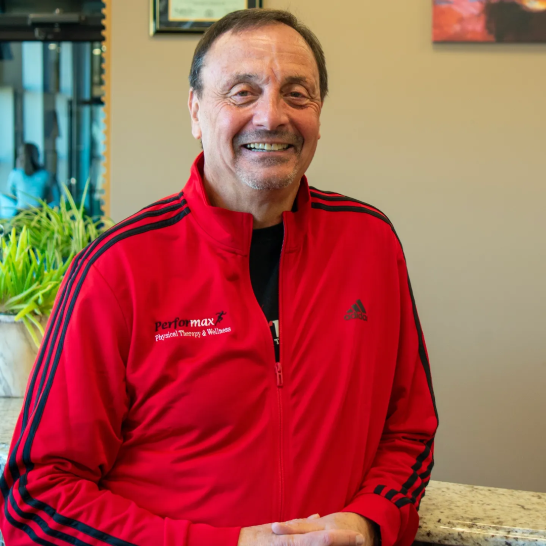 A man in red jacket smiling for the camera.