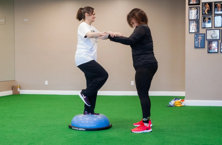 Two women are practicing balance on a bosu ball.