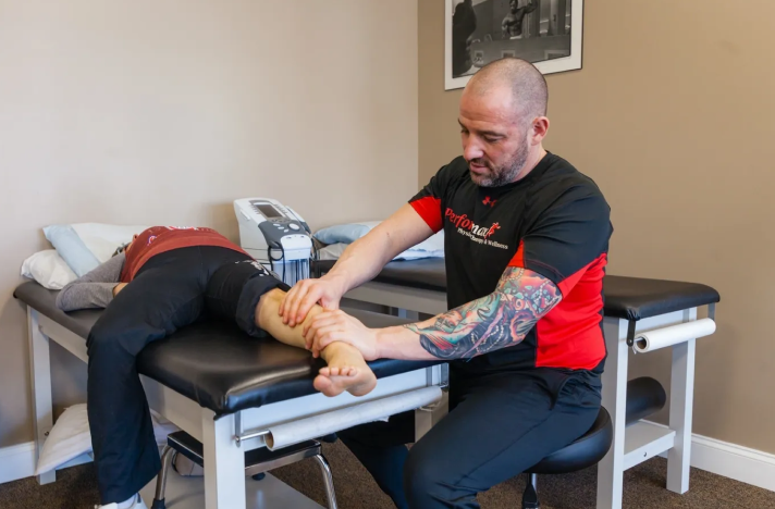 A man is sitting down and getting his foot examined.