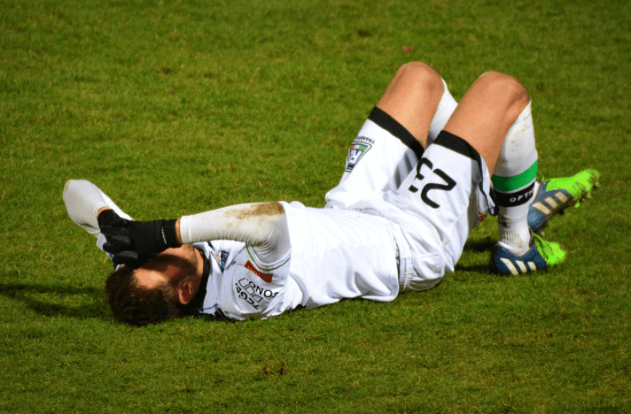 A soccer player laying on the ground after falling.