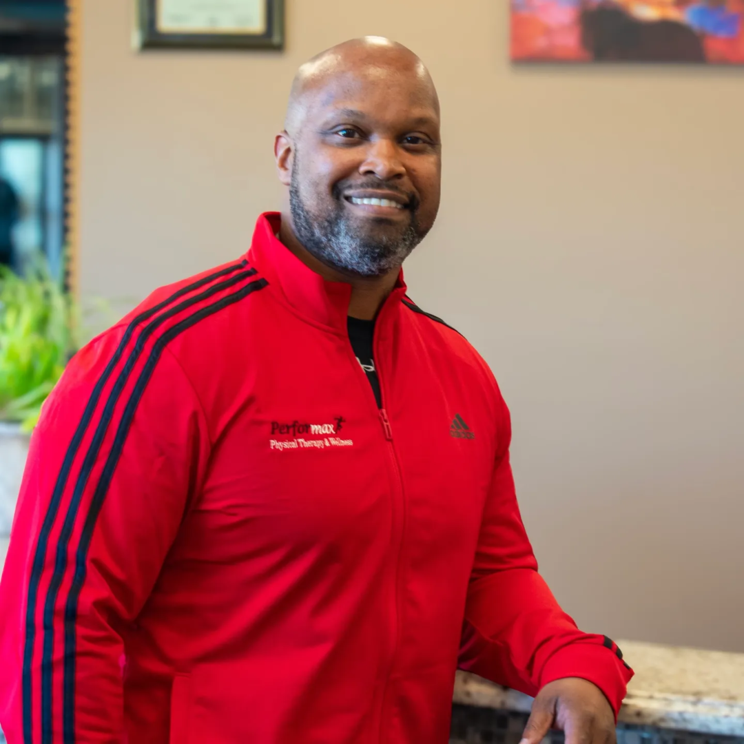 A man in red jacket standing next to a counter.