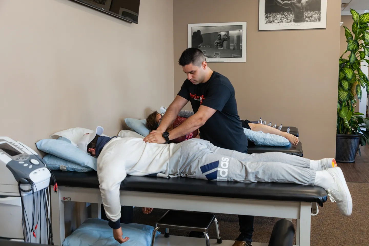 A man is stretching on the bed while another person lies down.