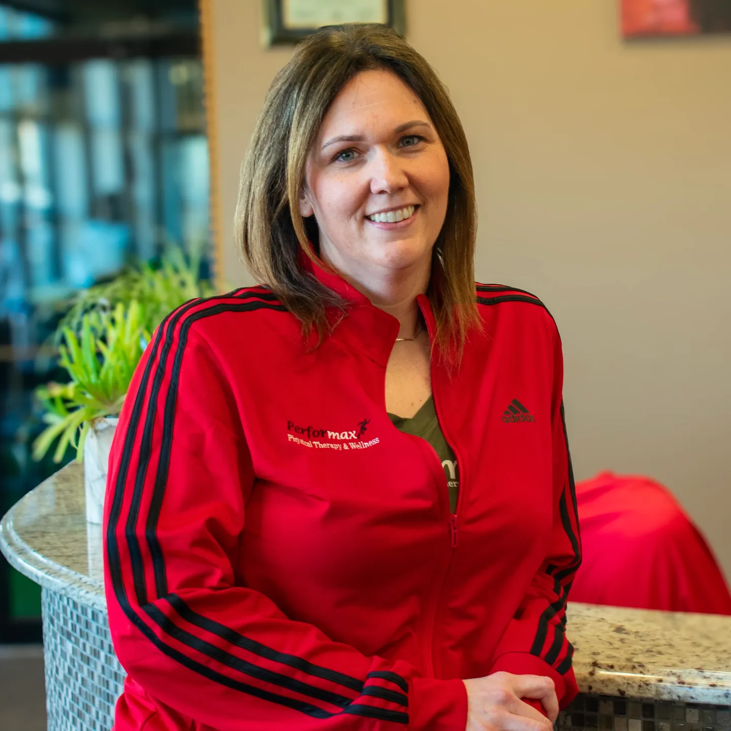 A woman in red jacket sitting on top of a table.