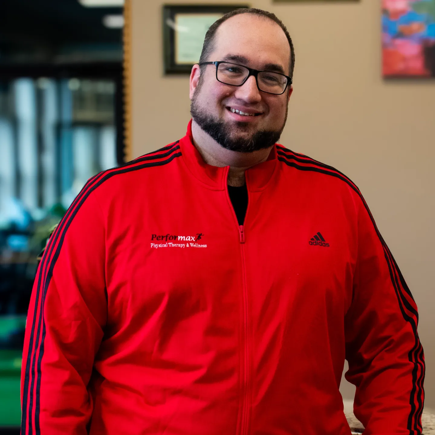 A man in red jacket standing next to wall.