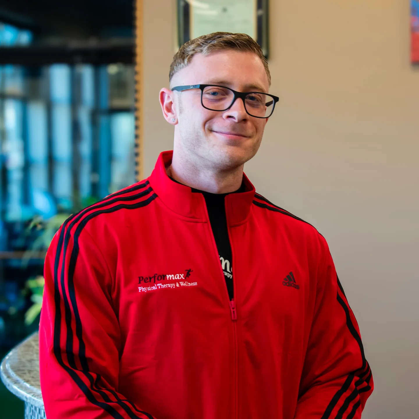 A man in red jacket standing next to wall.