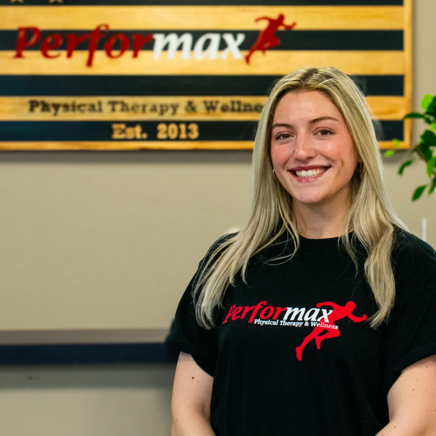 A woman standing in front of a wall with a logo on it.