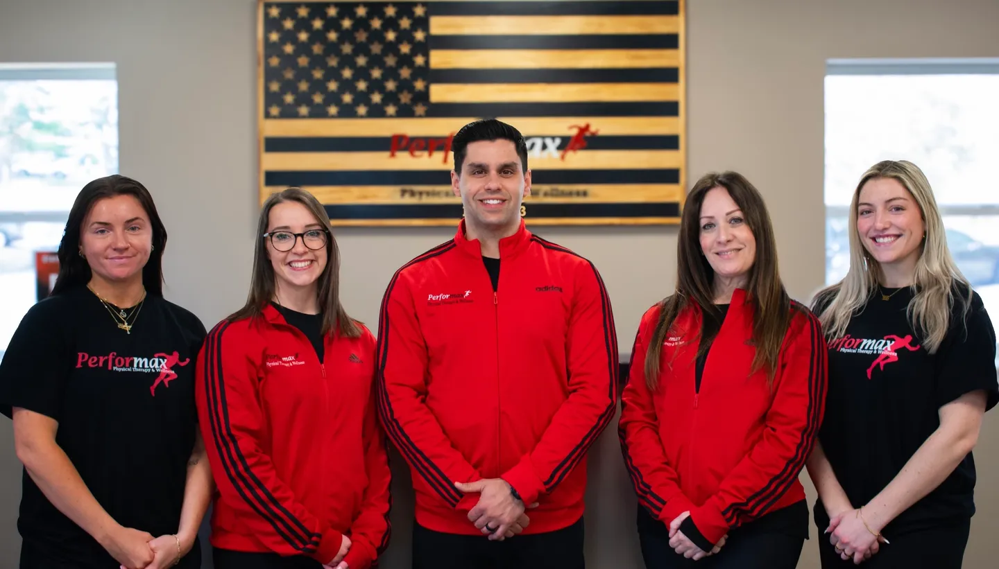 Three people in red jackets standing next to a flag.